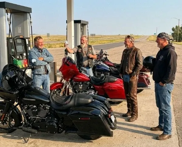 Vier motorrijders praten bij het tankstation, motoren uitgerust met SelleZen